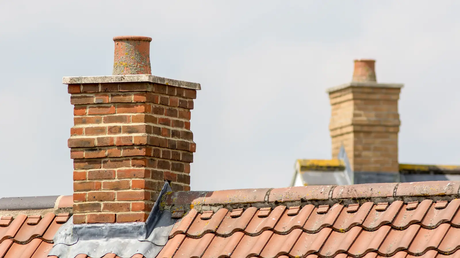 Brick chimney stacks on a red tiled roof