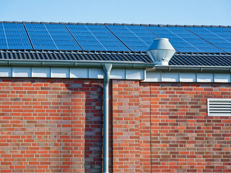 Brick commercial building with a sheet roof and rainwater pipes
