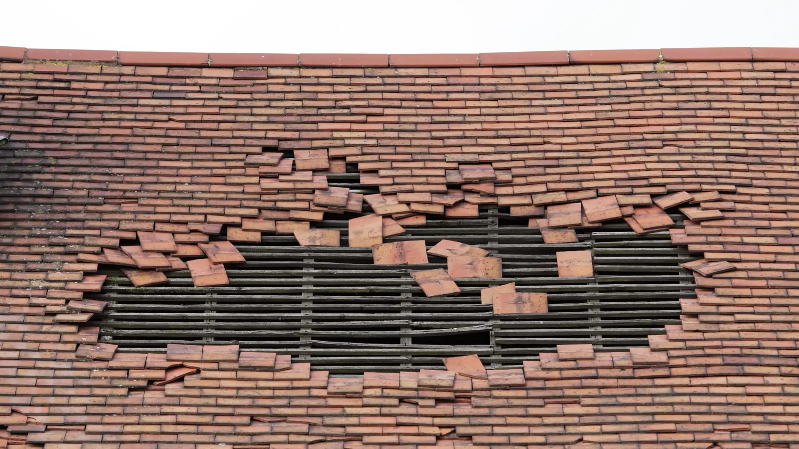 Storm damaged clay tile roof with tiles missing
