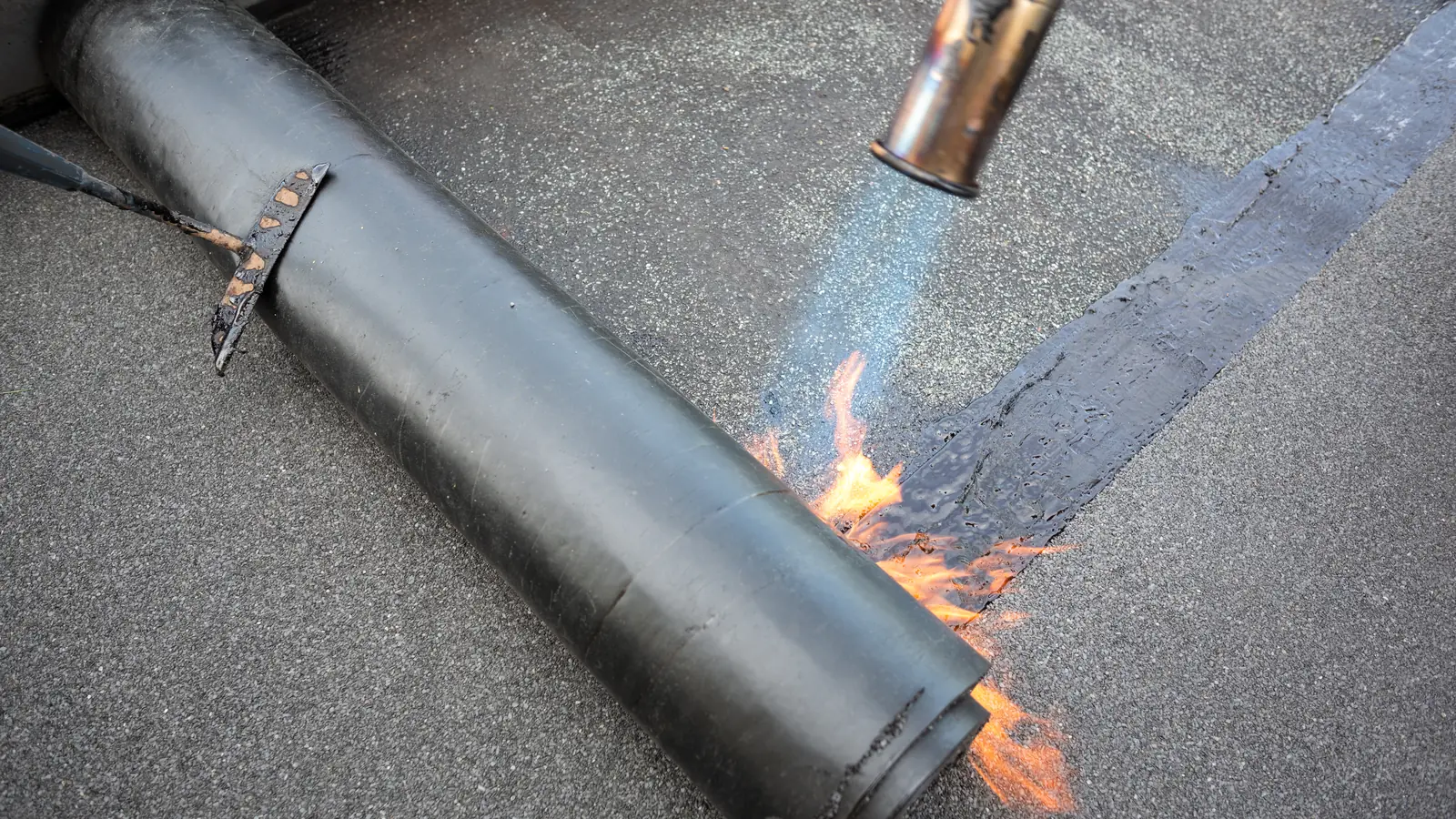 Torch-on felt being laid on a flat roof