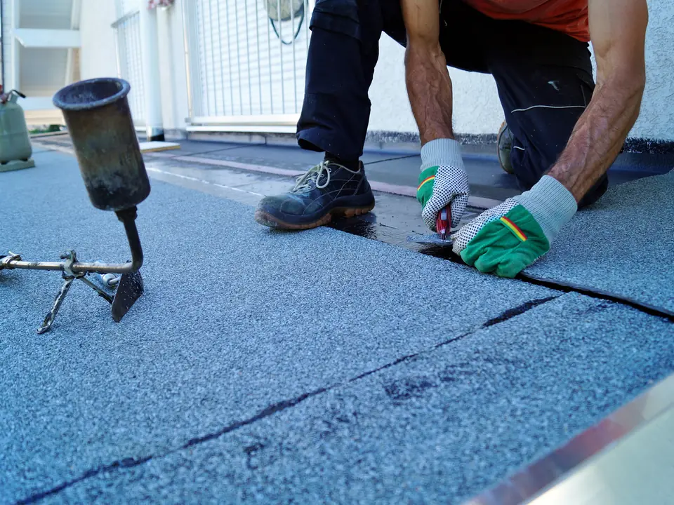 Felt flat roof being sealed by hand
