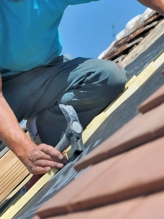 Roofer fixing replacement roof tiles by hand