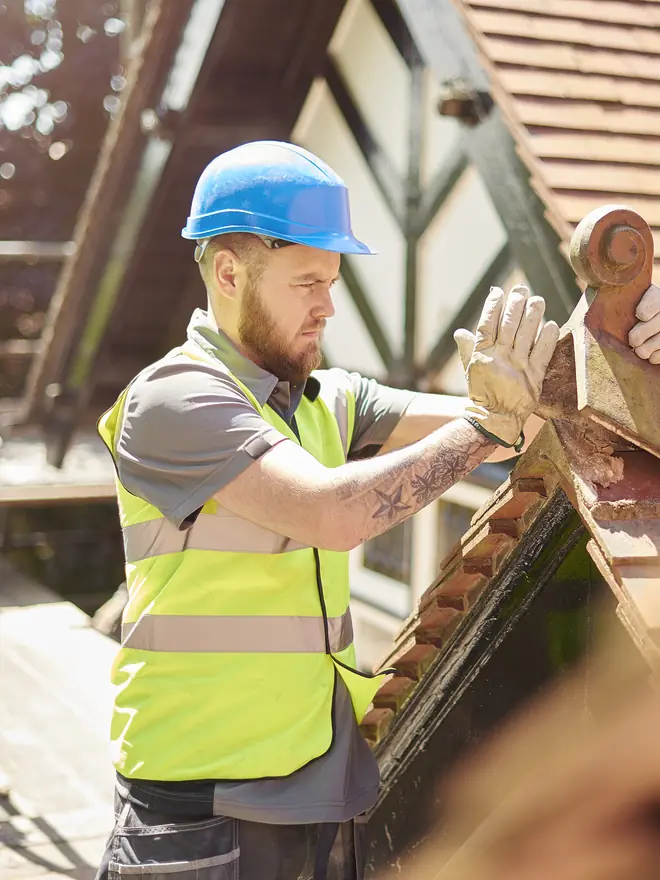 Roofer fitting a clay tile on a pitched roof